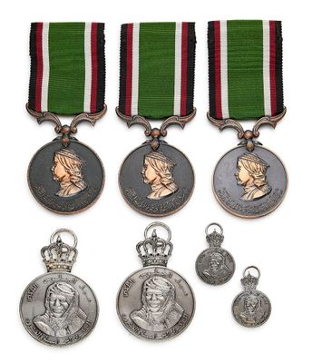 trois médailles et une médaille sont exposées sur un support blanc
