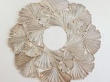 a silver wreath made of leaves on a white wall
