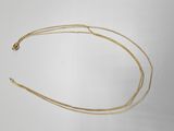 gros plan d'un collier en or sur une surface blanche