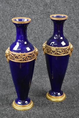 deux vases bleus ornés de touches dorées, posés sur une surface grise