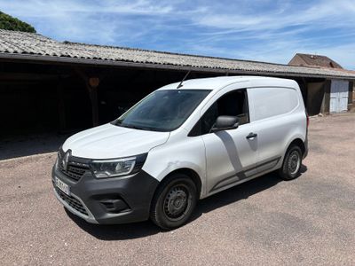La camionnette blanche est garée devant un garage.