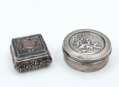 une petite boîte en argent et une petite boîte en argent posées sur une surface blanche