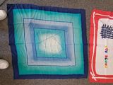 four pieces of quilt on the floor next to a pair of shoes