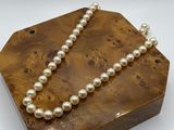 a close up of a wooden box with a pearl necklace on it