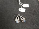 a pair of earrings sitting on a table next to a price tag