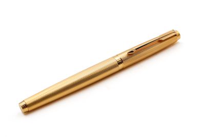 un stylo doré posé sur une surface blanche, avec un fond blanc