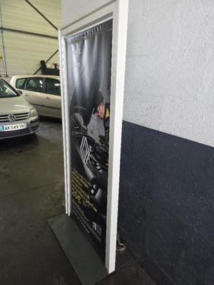 des voitures garées dans un parking couvert, avec une affiche sur le côté du bâtiment