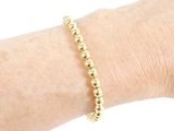 gold beaded bracelet on a woman ' s arm