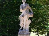 a statue of a woman sitting on a pedestal in the middle of a garden