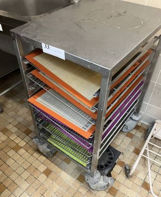 several trays of food sit on top of a metal cart in a kitchen