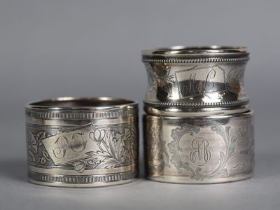 two silver napkins with designs on them sitting on a table