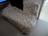 a couch that has a pillow on it in front of a flat screen tv