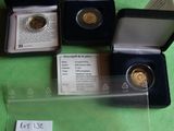 three gold coins are in a case on a green surface