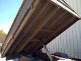a dump truck that is sitting in the back of it ' s trailer