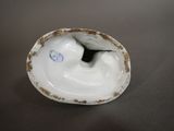 underside view of a porcelain figurine of a bird on a shell