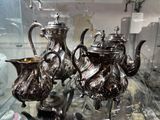 trois théières en argent exposées dans une vitrine