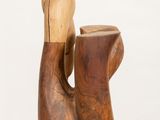 a wooden sculpture of a hand holding a vase