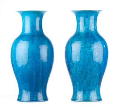 une paire de vases bleus posés sur une surface blanche, devant un fond blanc