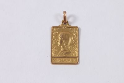 un gros plan d'un petit pendentif en or sur une surface blanche