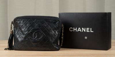 a black chanel bag sitting on top of a table next to a box