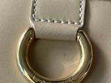 a close up of a white purse with a gold ring