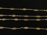 four pieces of gold colored metal with a chain on a black background
