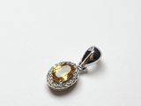 un gros plan d'un pendentif en diamants jaunes et blancs posé sur une surface blanche
