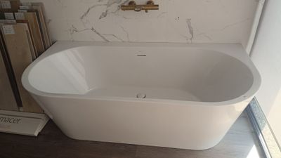 une baignoire blanche installée dans une salle de bains, près d'une fenêtre