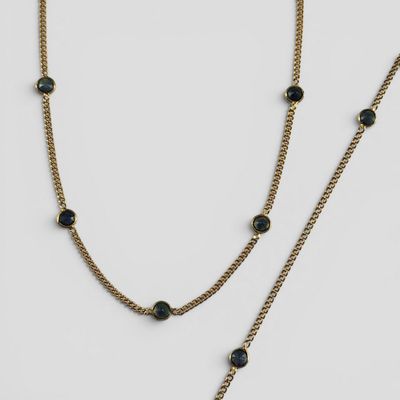 un gros plan sur un collier à chaîne en or orné de perles noires