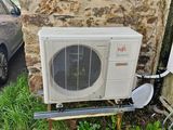 un climatiseur installé à l'extérieur d'une maison, à côté d'une voiture
