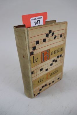 un vieux livre portant une étiquette rouge, posé sur une surface blanche