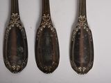 four spoons are lined up in a row on a white surface