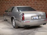 a silver car that is parked in front of a brick wall