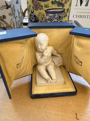 une petite statue représentant un bébé assis à l'intérieur d'une boîte