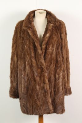 un manteau de fourrure marron posé sur un mannequin, devant un mur blanc