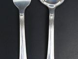 two spoons and a fork on a black table