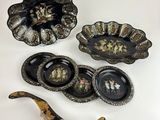 three pieces of black and gold decorated dishes and spoons