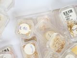 many different types of jewelry in plastic containers on a table
