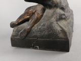 a bronze statue of a man laying on a rock