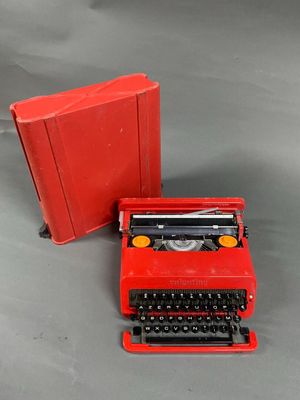 a red typewriter next to a red book