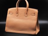 a tan leather handbag on a black background