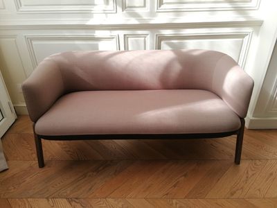 a pink couch sitting on a wooden floor in a room