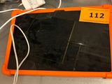 une tablette orange posée sur un comptoir, à côté d'un rouleau de papier toilette
