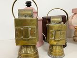 pair of antique brass oil lamps on a white table with a pink lamp