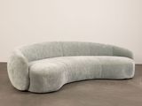 an image of a curved couch sitting on top of a cement floor