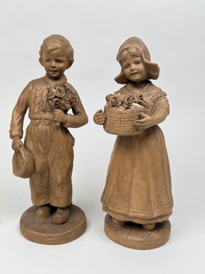 trois figurines représentant des enfants tenant des paniers de fleurs