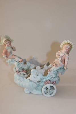 une figurine représentant deux enfants dans une calèche