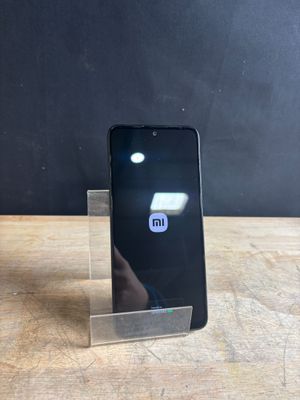 the back of a black cell phone sitting on top of a wooden table