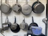 casseroles et poêles suspendues au mur d'une cuisine
