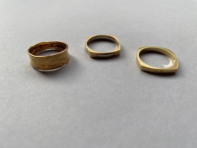 trois bagues en or posées les unes à côté des autres sur une table